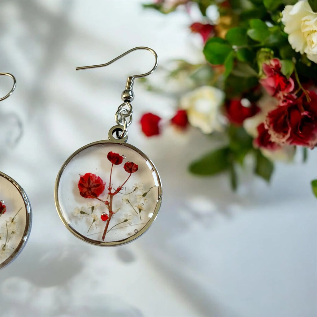 Boucles d’oreilles poussière de fée nellcréations en résine circulaire avec fleurs rouges et blanches préservées et cadre métal argenté