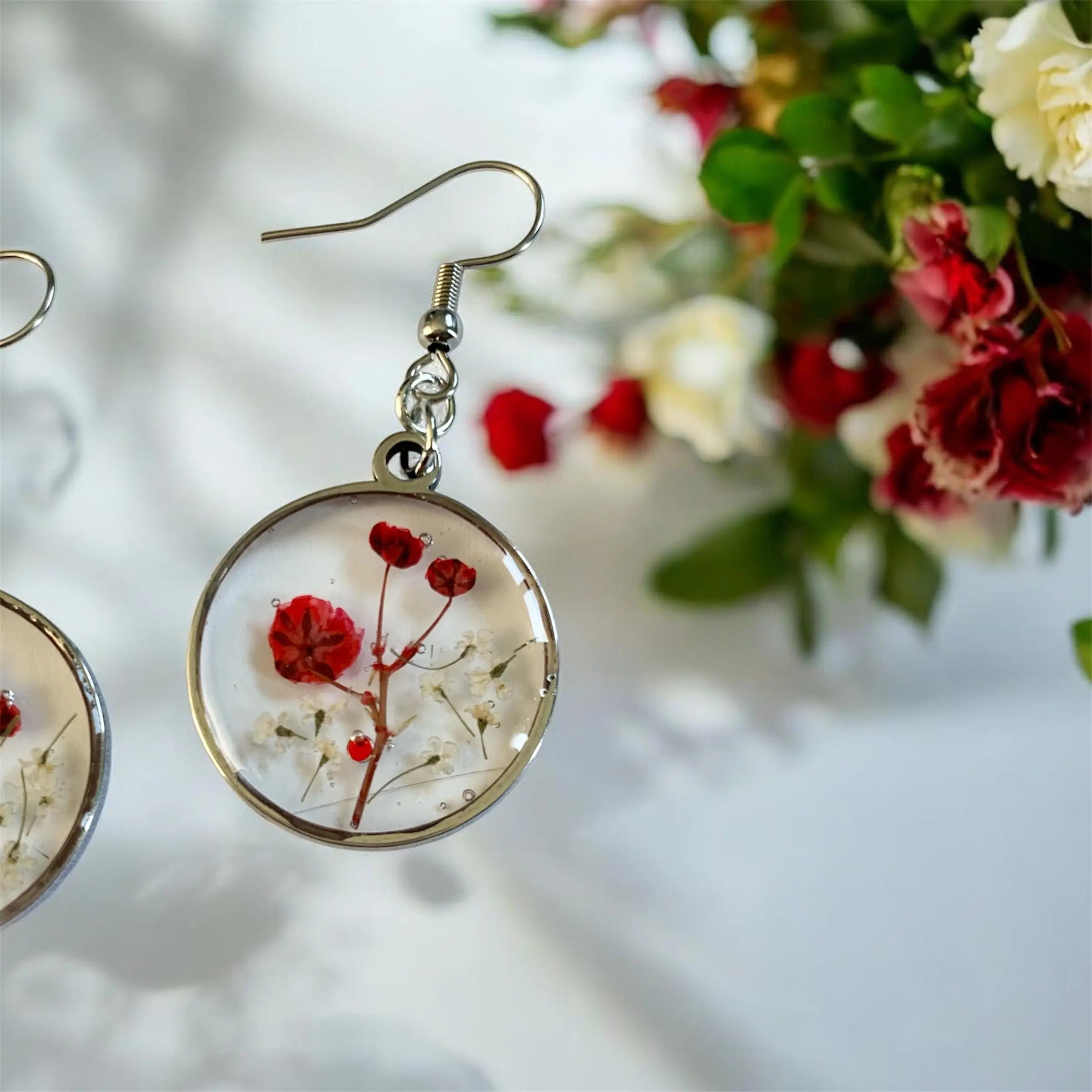 Boucles d’oreilles poussière de fée nellcréations en résine circulaire avec fleurs rouges et blanches préservées et cadre métal argenté