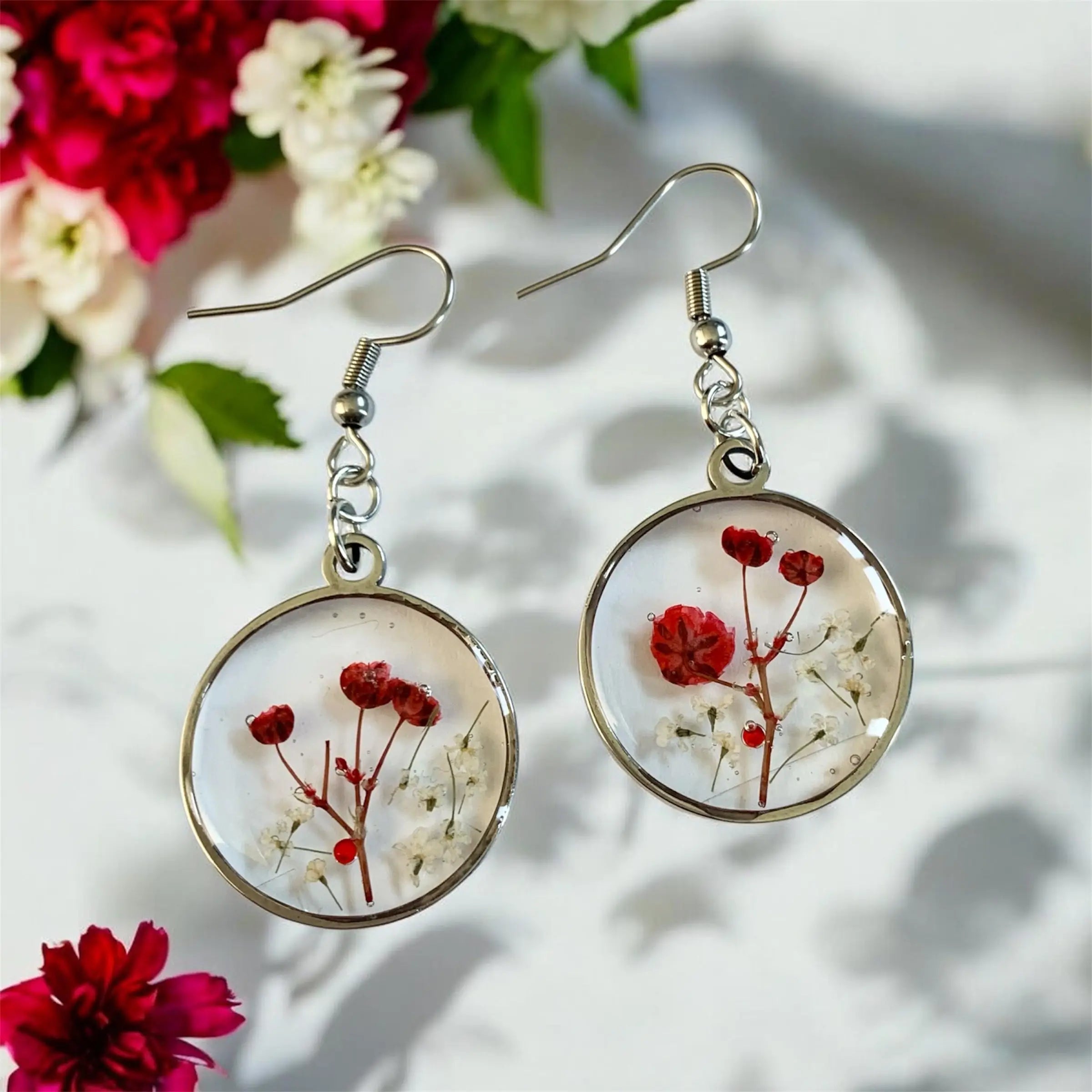Boucles d’oreilles circulaires en résine avec fleurs rouges et blanches préservées dans un cadre métal argenté Nellcréations