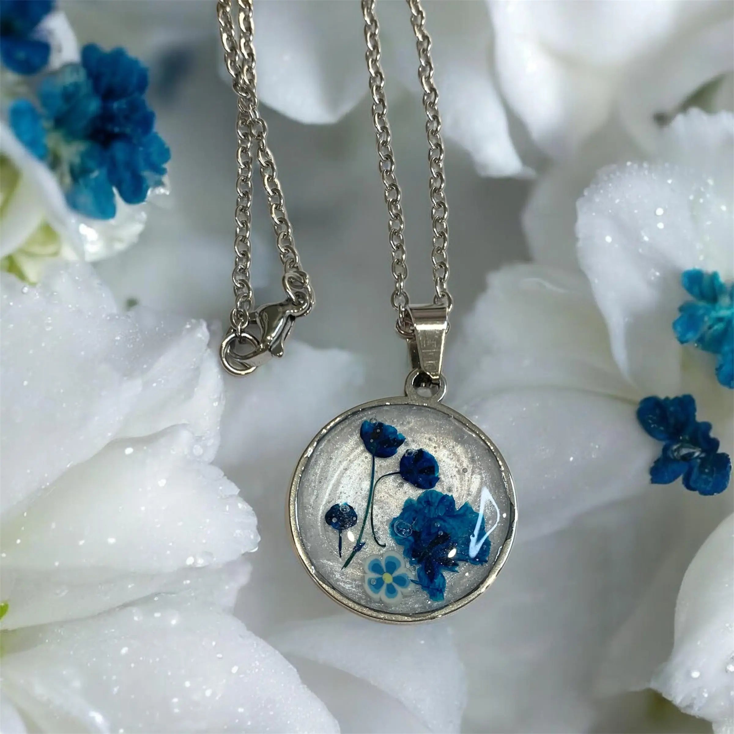 Collier jardin éternel bleu de nellcréations avec pendentif rond en résine contenant fleurs séchées bleues et blanches