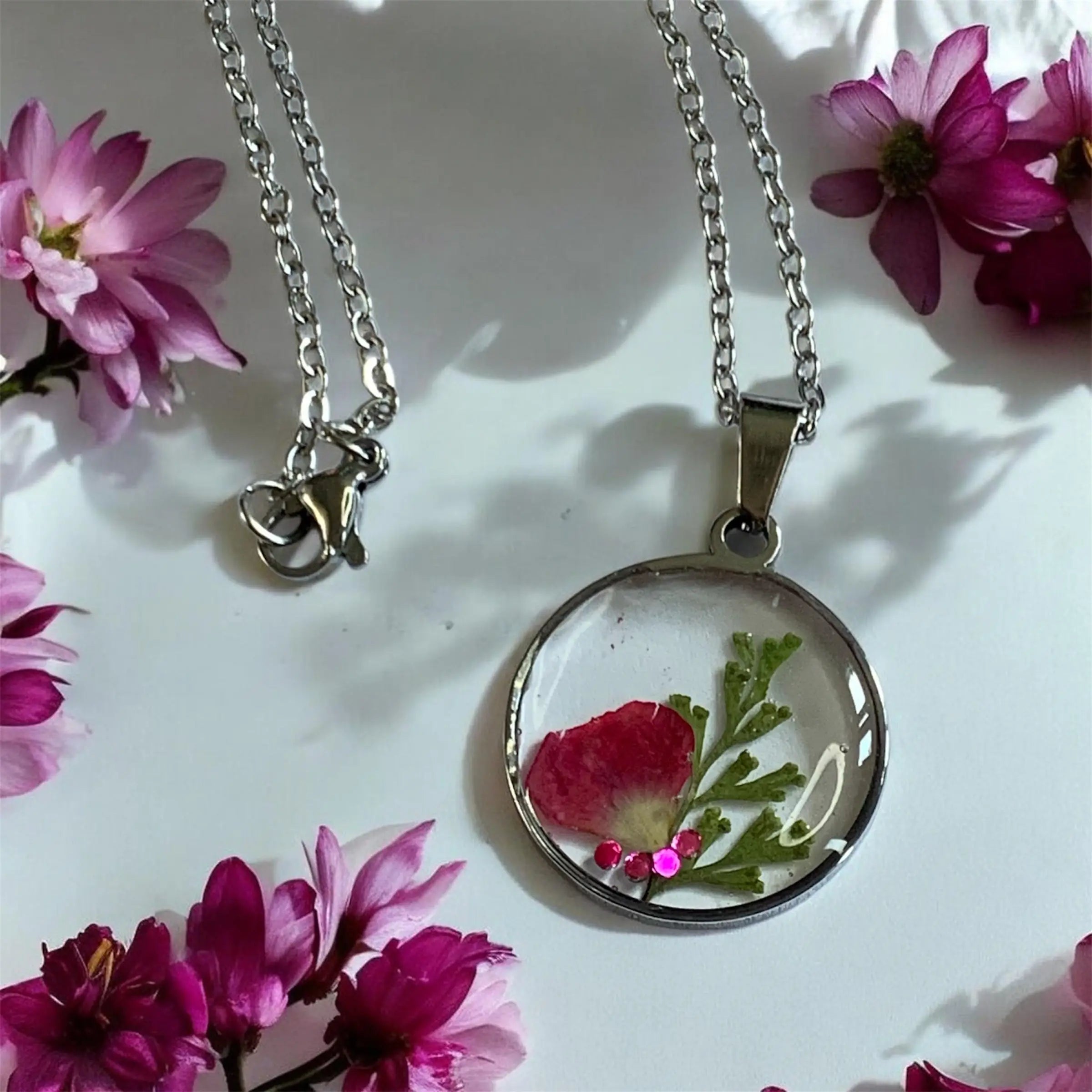 Collier rosa cristal de Nellcréations avec pendentif rond en résine clair contenant fleur rouge pressée et strass roses