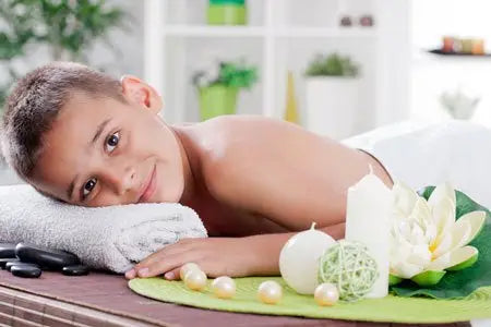 Une fleur de lotus blanche aux pétales délicats posée sur un tapis vert avec des pierres noires et perles pour un massage découverte enfants